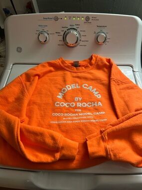 Coco Rocha Model Camp Orange Crewneck Sweatshirt with White Printed Text
